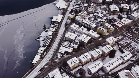 Frozen-Zell-lake,-view-of-white-snow-covered-roofs-of-Zell-Am-See-town,-aerial