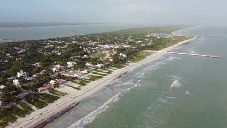 El-cuyo,-a-serene-beach-town-in-mexico-with-lush-greenery-and-a-quiet-beach,-aerial-view