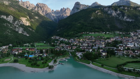 Molveno-establishing-aerial-view-over-picturesque-Dolomites-mountain-commune-and-lake-Molveno