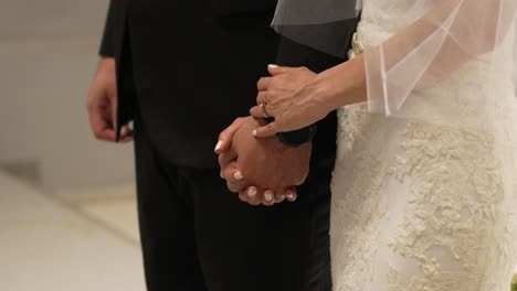 Bride-and-groom-holding-hands-in-front-of-the-altar-in-the-church-during-their-wedding-day