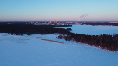 Aerial-view-over-the-sea,-toward-the-cityscape-of-Helsinki,-winter-evening-in-Finland