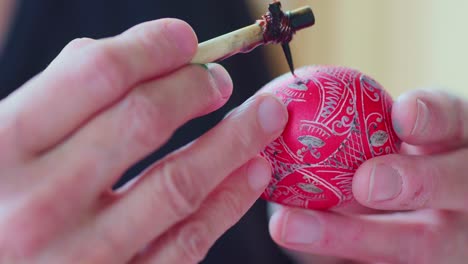 Close-up-on-Artist-Drawing-Traditional-Ornate-Designs-on-a-Red-Easter-Egg