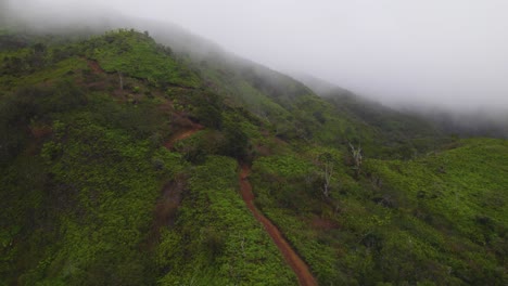 Panoramic-aerial-above-hiking-couple-climbing-down-dirt-trail-with-misty-clouds