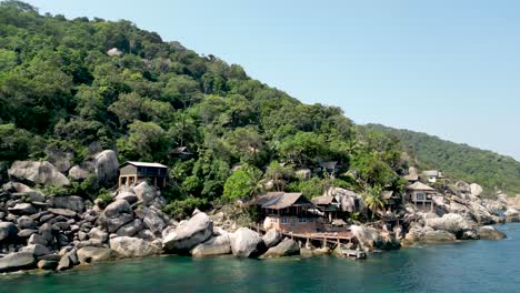 Seaside-cabins-on-rocks-in-Mango-Bay-Ko-Tao-Island-Thailand-by-shore,-Aerial-pan-left-shot