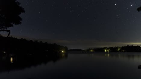 Sternennacht-Zeitraffer-über-Einem-Ruhigen-See-Mit-Silhouettierter-Küstenlinie