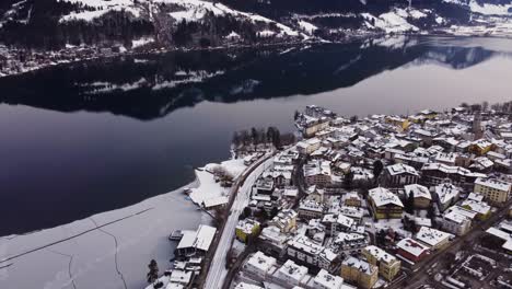 Breathtaking-winter-wonderland-town-in-Austria-Zell-Am-See-facing-lake,-aerial