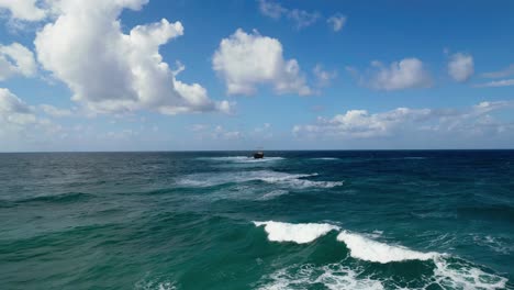 Blue-wavy-sea-with-shipwreck-in-the-center-under-a-partly-cloudy-sky,-off-the-coast-of-Cyprus