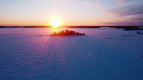 Drone-shot-over-snowy-ice-and-a-isle,-winter-evening-in-the-finnish-archipelago
