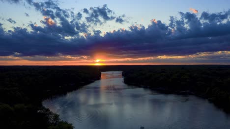 Aerial-View-of-Dramatic-Sunset-Over-Lake-With-Flowing-Clouds