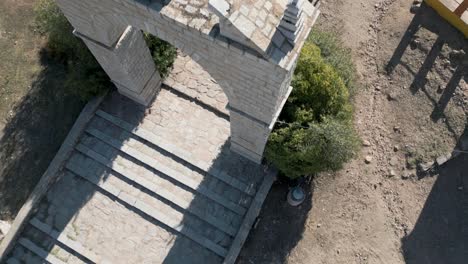 Aerial-top-down-shot-over-ruins-and-stone-archway-Spanish-church-entrance-gate