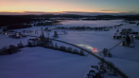 Verschneite-Landschaft-In-Der-Abenddämmerung-Mit-Straßen-Und-Verstreuten-Häusern,-In-Der-Nähe-Von-Sidensjö,-Schweden,-Luftaufnahme
