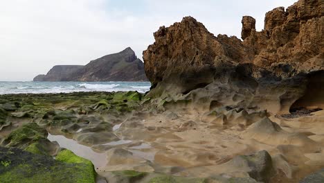 breathtaking-cinematic-seascape-with-erosion-rocks-covered-with-green-algae,-seawater-puddles-and-waves