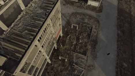 Rotating-aerial-shot-of-an-abandoned-destroyed-building-beside-empty-street-in-Prague-during-daytime