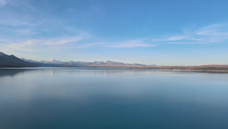 Panoramic-aerial-view-of-Lake-Pukaki-at-sunset,-surrounded-by-the-Southern-Alps,-in-New-Zealand