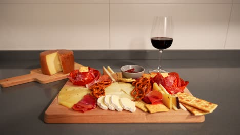 Female-hands-taking-a-red-wine-glass-next-to-a-cheeseboard-with-bread-and-pretzels