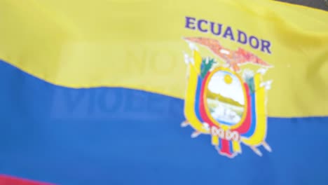No-violence-in-Latin-America,-waving-flag-of-Ecuador-over-sign-in-english