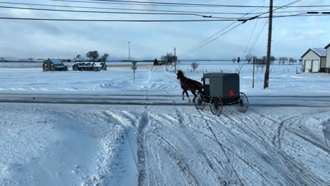 Aerial-tracking-shot-of-horse-and-buggy-in-snow-covered-Amish-country