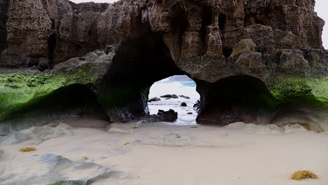 Natural-Geology-rock-islet-cave-tunnel-caused-by-sea-erosion-on-sandy-beach-on-the-Porto-Santo-island-in-Portugal,-50fps-HD-static-shot