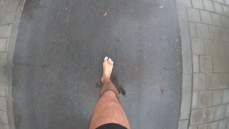 man-running-barefoot-wearing-shorts-running-on-asphalt-road-using-go-pro-on-body