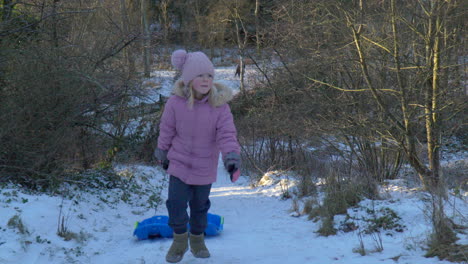 Zeitlupe-Eines-Mädchens,-Das-Mit-Zwei-Bobschlitten-Einen-Schneebedeckten-Hügel-Hinaufläuft