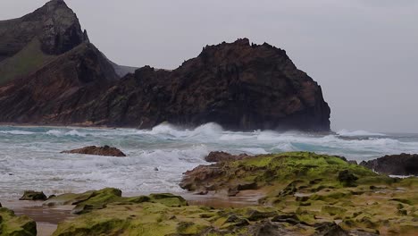 Turbulente-Und-Aufgeregte-Wellenströmungen-Am-Sandstrand-Mit-Meerwasserfelsen-Und-Einer-Insel-Im-Hintergrund,-50-Fps-Insel-Porto-Santo