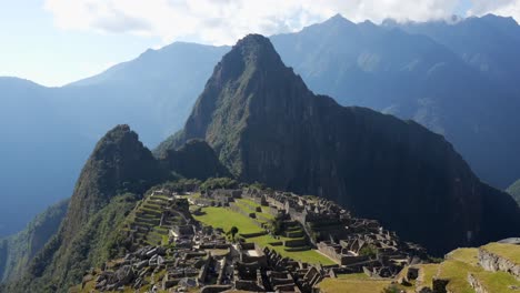 Drone-view-of-mysterious-Inca-ruins-at-Machu-Picchu-shrouded-in-mist-high-in-the-Andes-mountains,-Cusco-Region,-Peru