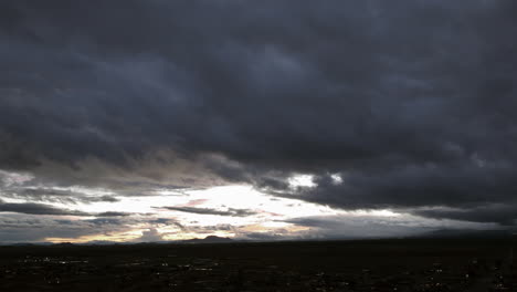 Dramatic-sky-at-dusk-with-sunlight-piercing-through-storm-clouds,-expansive-view,-timelapse
