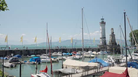 Sunny-day-at-Lindau-Harbor-with-boats,-lighthouse,-and-statues,-clear-blue-sky