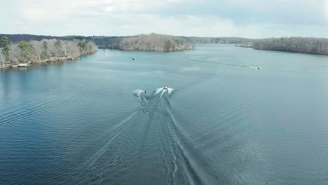 Schnellboot-Schleppt-Wasserskifahrer-Auf-Einem-Ruhigen-See,-Luftaufnahme