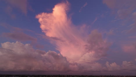 Wispy-flare-of-pink-red-golden-hour-glow-on-cloud-above-purple-sunset-sky