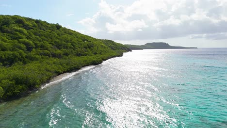 Das-Licht-Glitzert-Auf-Dem-Türkisfarbenen-Wasser,-Während-Die-Trockene-Karibische-Inselvegetation-An-Die-Strandküste-Rollt