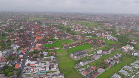Villa-and-village-homes-surround-rice-fields-in-Canggu-Bali,-aerial-establish