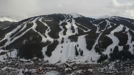 Aerial-Drone-Copper-Mountain-Colorado-Ikon-Epic-Pass-winter-spring-cloudy-snowy-afternoon-sunset-last-light-half-pipe-chairlift-ski-runs-center-village-cinematic-slowly-forward-down-motion