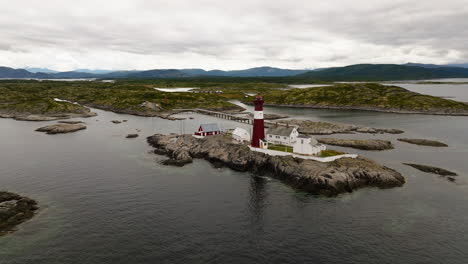 Aerial-orbit-establishes-Tranoy-island-lighthouse-and-historic-footbridge,-Norway
