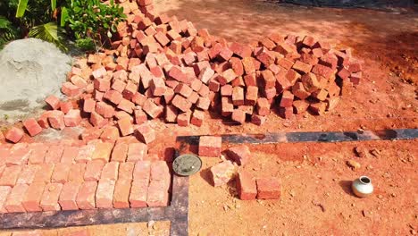 The-red-blocks-were-piled-up,-Construction-using-earthen-blocks,-Building-the-foundation-of-the-house,-Workers-work-at-a-construction-site-in-India,-Building-a-house-with-red-stone-