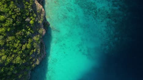 Luftaufnahmen-Von-Oben-Nach-Unten-über-Dem-Sandigen-Korallenriff,-Das-Von-Geheimnisvollen-Tropischen-Klippen-Abfällt