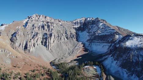 Drone-shot-panning-up-on-steep-rocky-mountain-peaks-in-Telluride,-CO