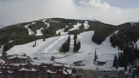 Aerial-Drone-Copper-Mountain-Colorado-Ikon-Epic-Pass-winter-spring-cloudy-snowy-afternoon-sunset-last-light-half-pipe-Flyer-chairlift-ski-runs-center-village-cinematic-slowly-reveal-forward-motion