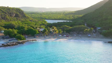 Slow-aerial-pan-across-turquoise-blue-water-and-palm-trees-of-Daaibooi-beach-curacao