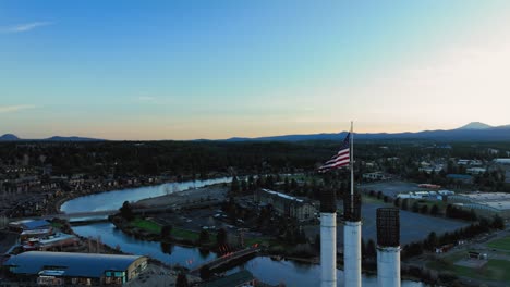 Drone-shot-of-the-American-Flag-waving-over-Bend,-Oregon-at-sunset