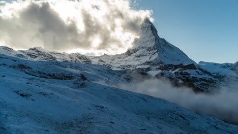 Zermatt-The-Matterhorn-Timelapse-The-Gornergrat-Switzerland-late-afternoon-sunset-clouds-on-fire-on-adjacent-mountain-face-landscape-golden-yellow-sunset-cool-blue-shade-rolling-fog-still-motion