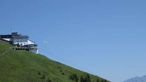 Hang-glider,-gracefully-soar-through-the-air-passing-behind-resort-building