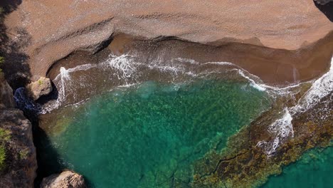 Drone-descends-on-playa-Santu-Pretu-black-sand-beach-cove-as-waves-crash-on-shore