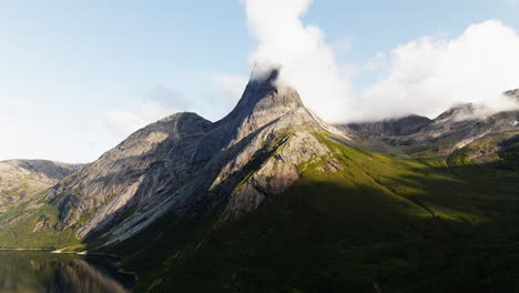 El-árido-Pico-De-La-Montaña-Con-Una-Pendiente-Cubierta-De-Hierba-Domina-El-Lago-Mientras-Las-Nubes-Se-Reúnen-En-La-Cima,-Stetind-Noruega
