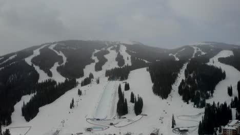 Aerial-Drone-Copper-Mountain-Colorado-Ikon-Epic-Pass-winter-spring-cloudy-snowy-early-morning-first-light-gray-bird-half-pipe-chairlift-ski-runs-center-village-gondola-cinematic-circle-left-slowly