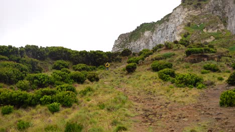 Hombre-De-Chaqueta-Amarilla-Caminando-Por-El-Lado-Verde-Del-Morro-De-Castelo-Branco-En-Faial,-Azores