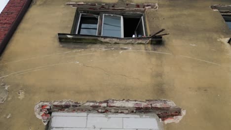 Low-angle-dolly-movement-shot-on-broken-windows-of-a-crumbling-abandoned-building