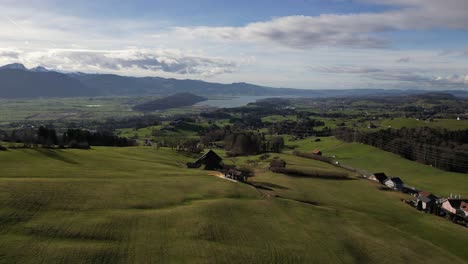 Establishing-Cinematic-Aerial-of-Open-Fields-with-Beautiful-Lake-and-Mountains-in-Background