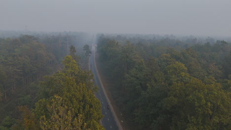 Drone-shot-of-Nepal-Highway-inside-the-wild-forest-covered-with-fog-and-smoke