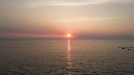 Erstaunlicher-Roter-Sonnenuntergang-Tief-Am-Horizont-über-Dem-Wasser